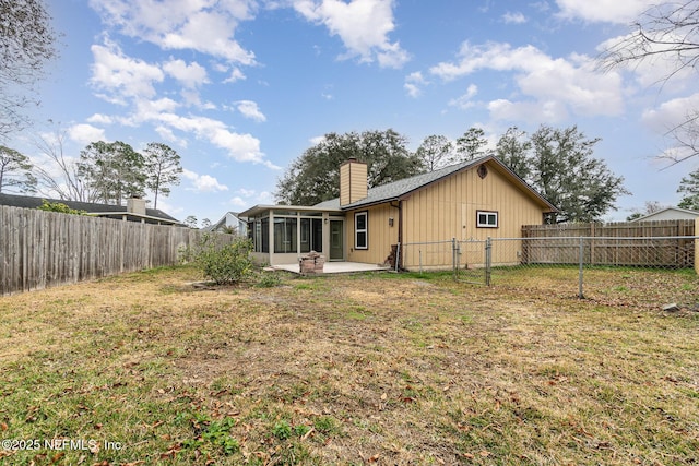 rear view of property with a yard, a patio area, and a sunroom