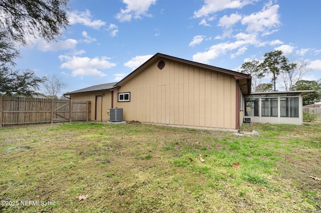 view of side of property featuring a sunroom, a yard, and cooling unit