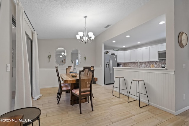 dining area with an inviting chandelier and a textured ceiling