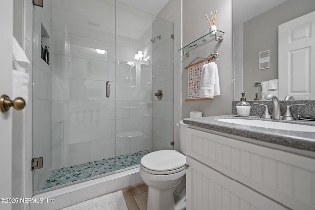 bathroom with a shower with door, vanity, and toilet