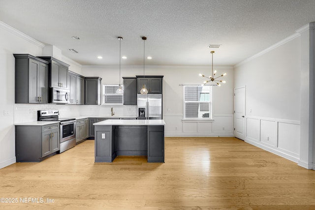 kitchen featuring stainless steel appliances, a kitchen island, hanging light fixtures, and gray cabinetry