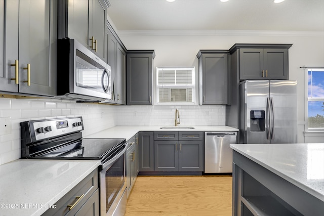 kitchen with sink, gray cabinetry, ornamental molding, stainless steel appliances, and decorative backsplash