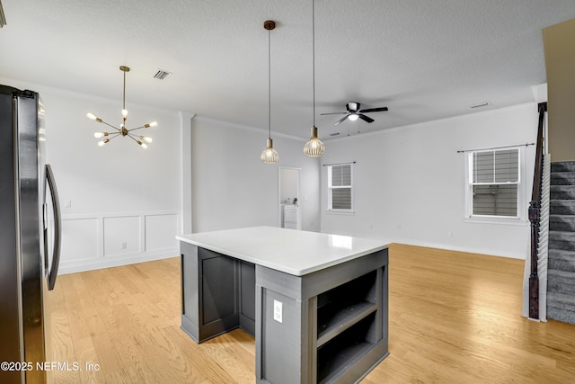 kitchen with stainless steel fridge, a center island, ornamental molding, light hardwood / wood-style floors, and a textured ceiling