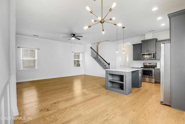 kitchen with decorative light fixtures, gray cabinetry, a center island, light hardwood / wood-style floors, and stainless steel appliances