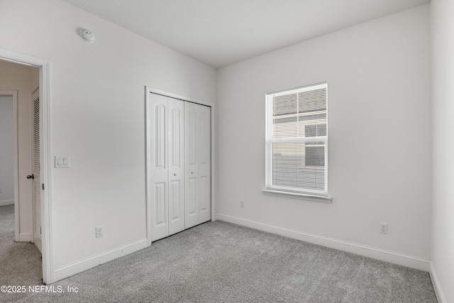 unfurnished bedroom featuring light colored carpet and a closet