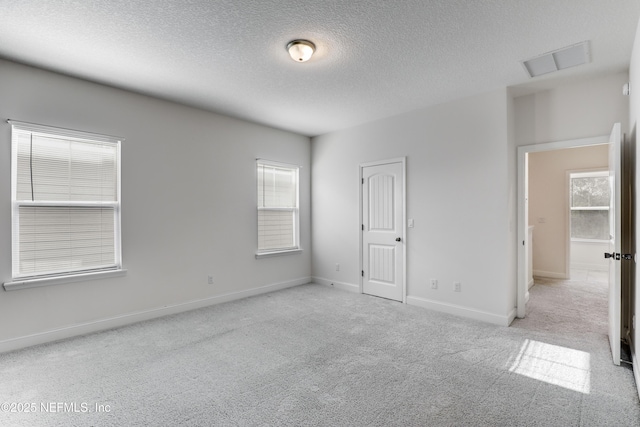 carpeted empty room with a textured ceiling