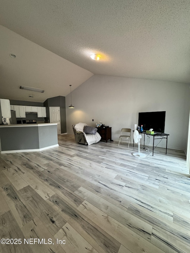 unfurnished living room featuring vaulted ceiling, a textured ceiling, and light hardwood / wood-style floors