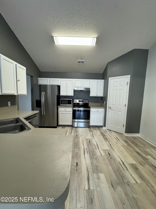 kitchen featuring lofted ceiling, stainless steel appliances, and white cabinets