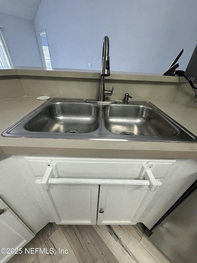 room details featuring white cabinetry, sink, and light wood-type flooring