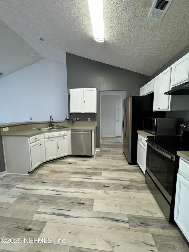 kitchen featuring lofted ceiling, sink, white cabinetry, light wood-type flooring, and stainless steel appliances