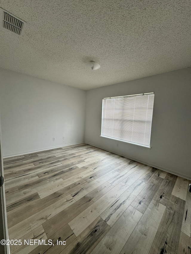 empty room featuring light hardwood / wood-style floors and a textured ceiling