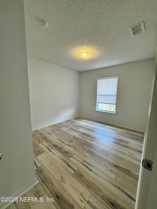 unfurnished room featuring a textured ceiling and light wood-type flooring