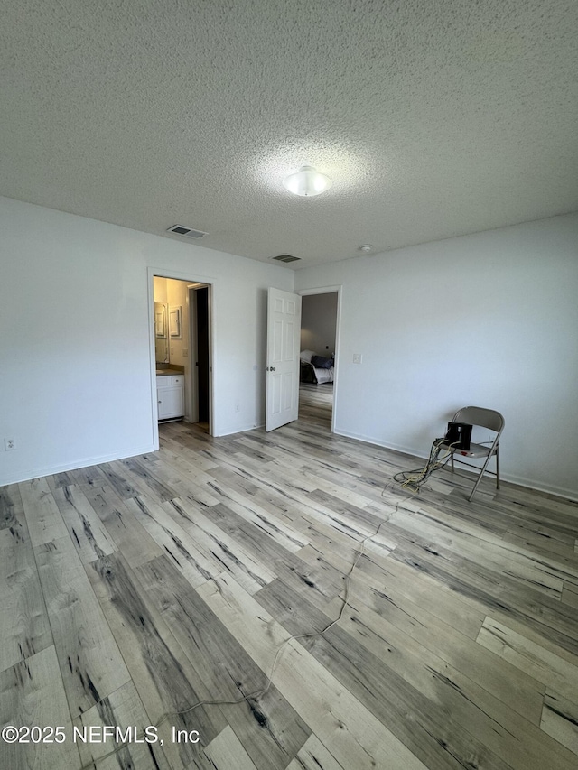 unfurnished bedroom with a textured ceiling and light wood-type flooring