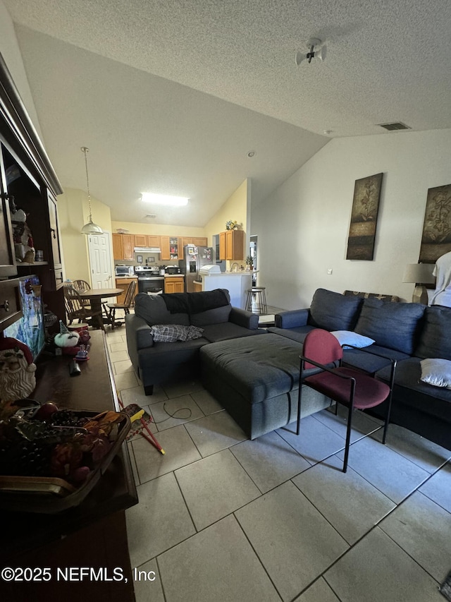 tiled living room featuring vaulted ceiling and a textured ceiling