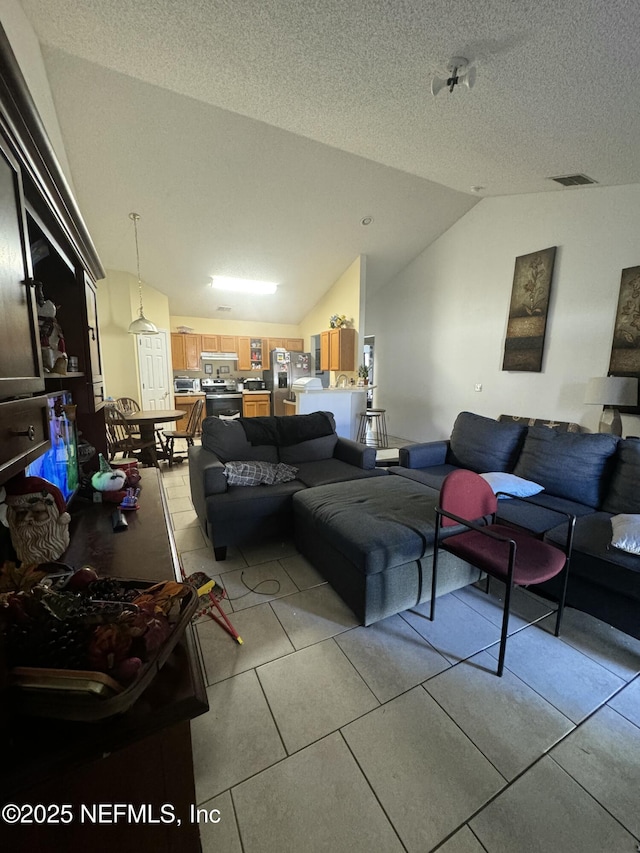 living room with vaulted ceiling, light tile patterned flooring, and a textured ceiling