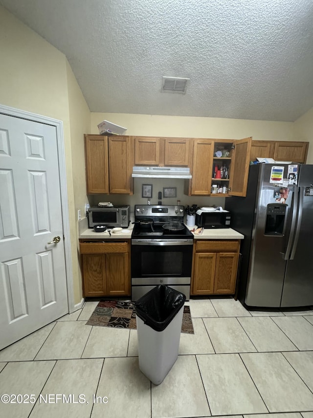 kitchen with appliances with stainless steel finishes, light tile patterned floors, and a textured ceiling