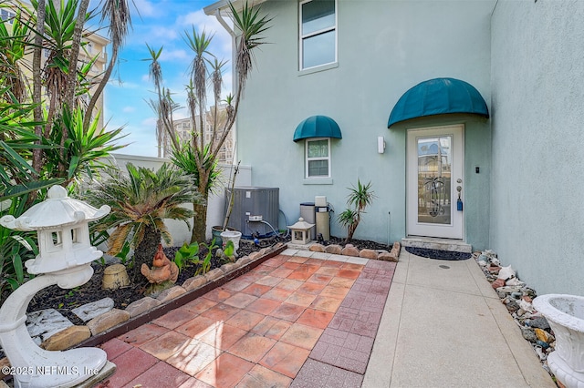 view of exterior entry featuring central AC unit and a patio