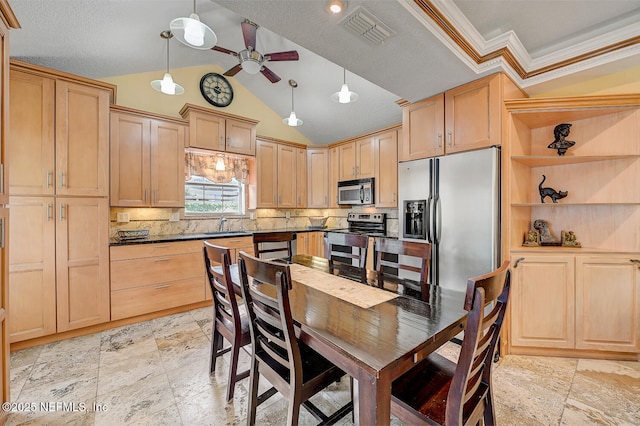 kitchen featuring appliances with stainless steel finishes, light brown cabinetry, and hanging light fixtures