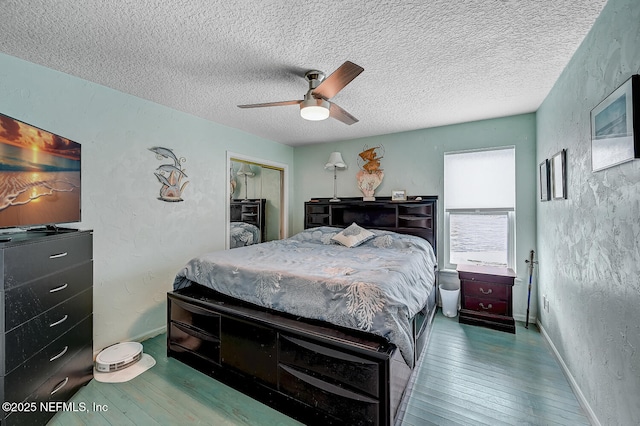 bedroom featuring ceiling fan, wood-type flooring, a closet, and a textured ceiling