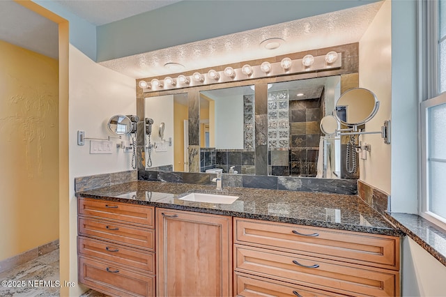 bathroom with vanity, a textured ceiling, and tiled shower