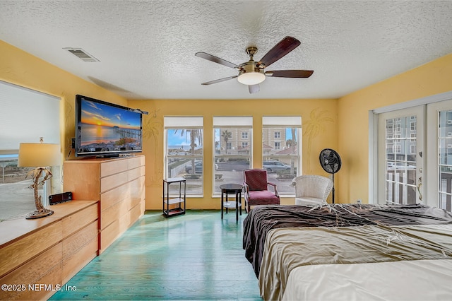 bedroom with ceiling fan, hardwood / wood-style flooring, french doors, and a textured ceiling