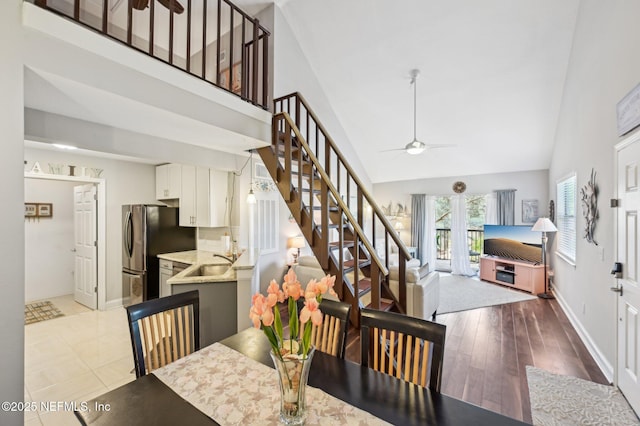 dining room featuring ceiling fan, high vaulted ceiling, light hardwood / wood-style floors, and sink