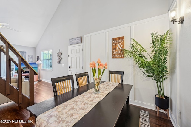 dining area with high vaulted ceiling and dark hardwood / wood-style floors