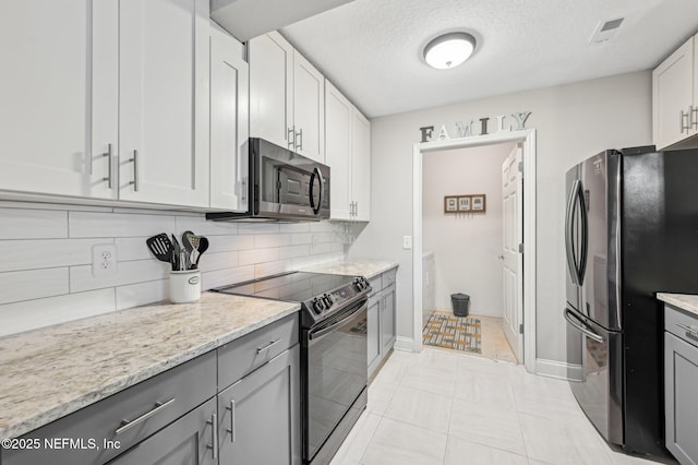 kitchen with light stone counters, a textured ceiling, stainless steel appliances, decorative backsplash, and white cabinets