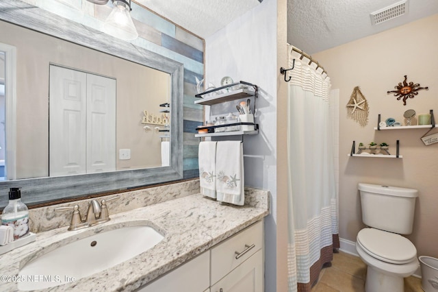 bathroom featuring vanity, tile patterned floors, a textured ceiling, and toilet