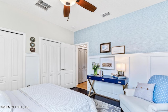 bedroom featuring hardwood / wood-style flooring, two closets, and ceiling fan