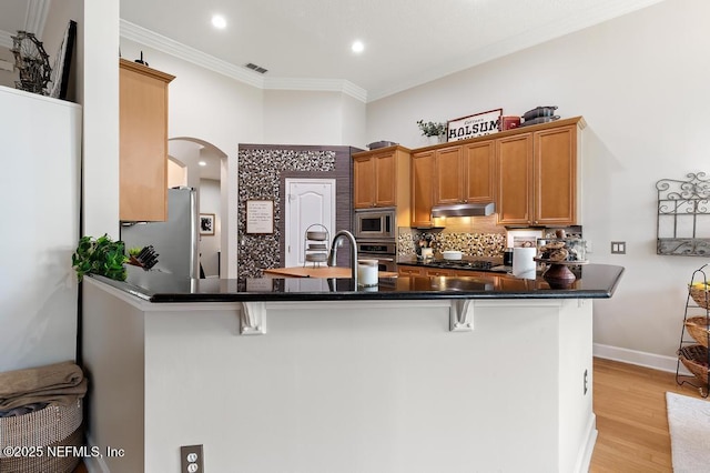 kitchen featuring a breakfast bar area, tasteful backsplash, ornamental molding, appliances with stainless steel finishes, and kitchen peninsula