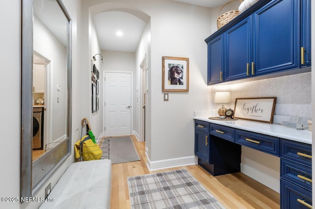 interior space featuring washer / clothes dryer, decorative backsplash, light hardwood / wood-style flooring, and blue cabinets