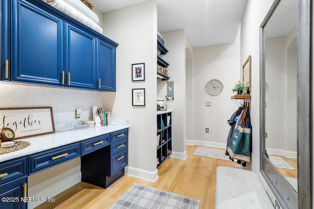 interior space with tasteful backsplash, blue cabinets, and light hardwood / wood-style flooring