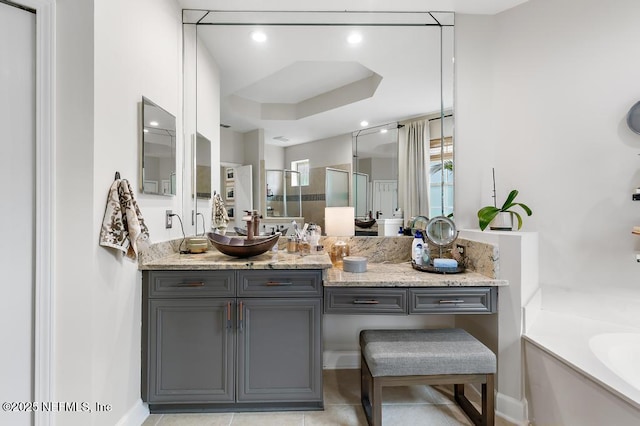 bathroom featuring vanity, a tub to relax in, a tray ceiling, and tile patterned flooring