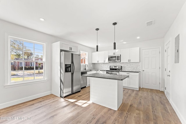 kitchen with hanging light fixtures, stainless steel appliances, a center island, and white cabinets