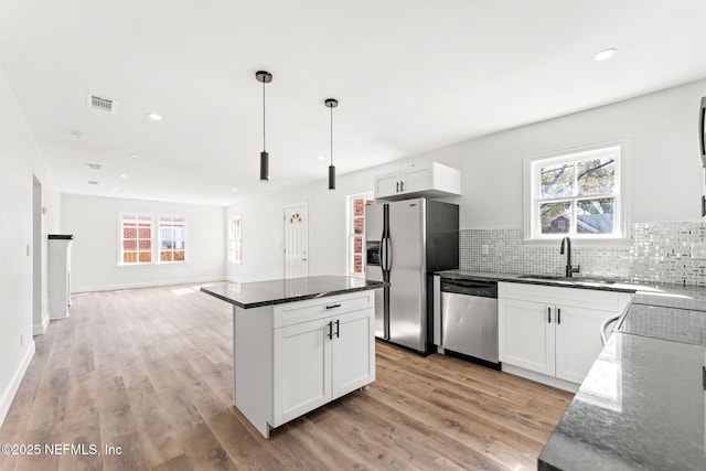 kitchen featuring sink, decorative light fixtures, appliances with stainless steel finishes, dark stone counters, and white cabinets