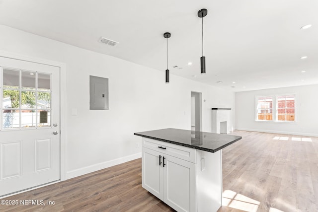 kitchen featuring pendant lighting, white cabinetry, a center island, electric panel, and hardwood / wood-style flooring