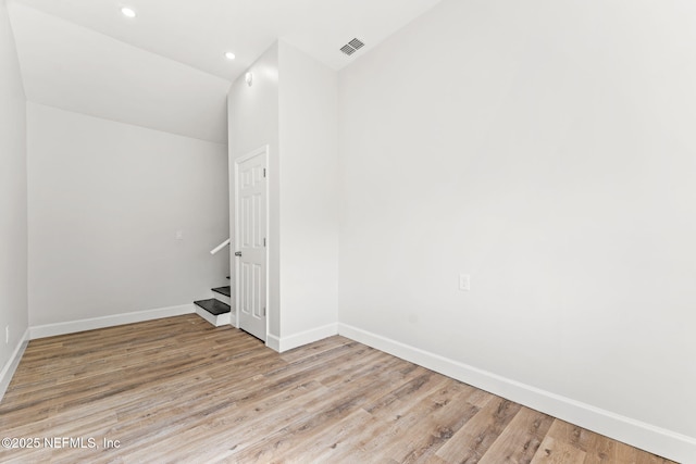 unfurnished room with vaulted ceiling and light wood-type flooring