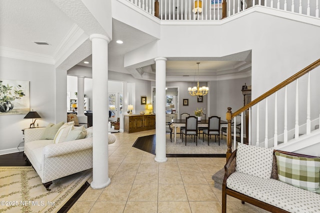 tiled entryway with ornate columns, a chandelier, a high ceiling, ornamental molding, and a textured ceiling