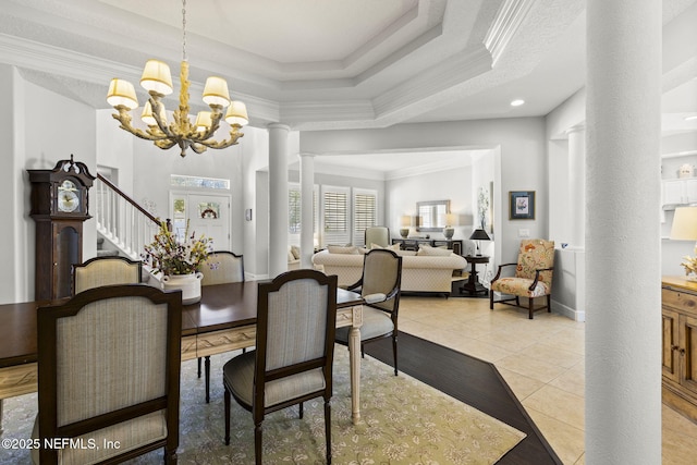 dining area with crown molding, a chandelier, light tile patterned floors, a raised ceiling, and decorative columns