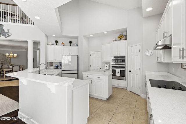 kitchen featuring sink, white refrigerator, white cabinets, and a center island with sink