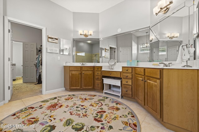 bathroom featuring a towering ceiling, vanity, a notable chandelier, a shower with shower door, and tile patterned floors