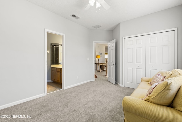 living area featuring light carpet, ceiling fan, and a textured ceiling