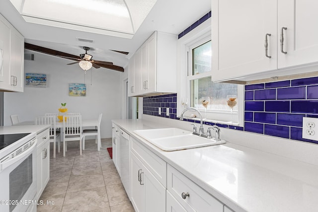 kitchen with sink, white appliances, tasteful backsplash, white cabinets, and light tile patterned flooring