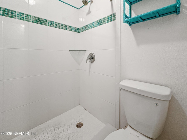 bathroom featuring toilet and a tile shower