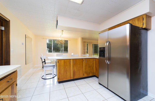 kitchen with light tile patterned flooring, a breakfast bar, stainless steel fridge, kitchen peninsula, and pendant lighting