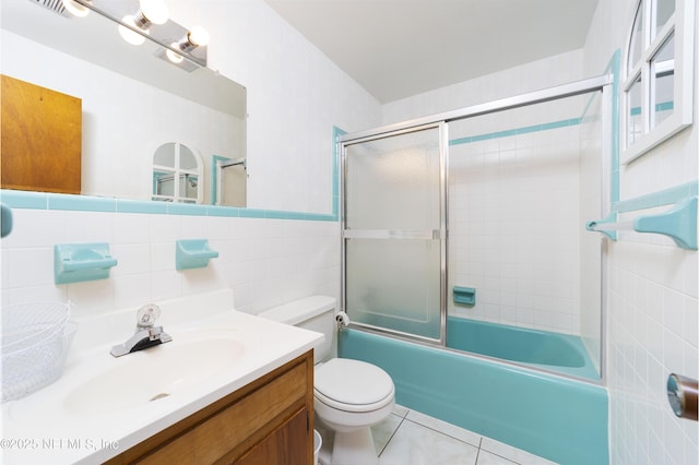 full bathroom featuring tile patterned floors, toilet, bath / shower combo with glass door, tile walls, and vanity