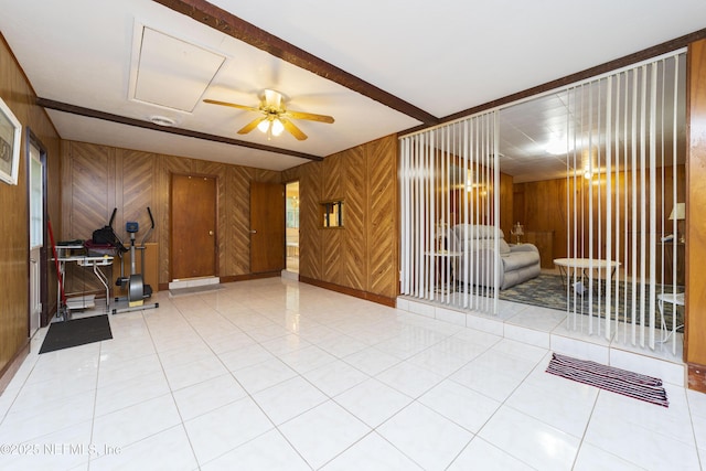 tiled spare room featuring ceiling fan, beamed ceiling, and wood walls