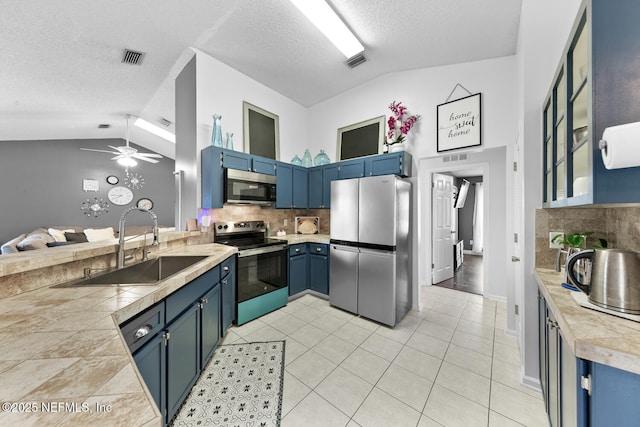 kitchen featuring decorative backsplash, blue cabinets, vaulted ceiling, stainless steel appliances, and light countertops