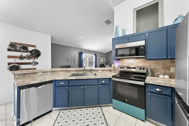 kitchen featuring light countertops, appliances with stainless steel finishes, a peninsula, and a sink